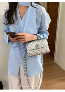 Silver quilted chain shoulder bag with classic metal lock design for women fashion.