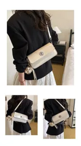 Detail shot of elegant beige women shoulder bag with metal lock and cute bear pendant charm.