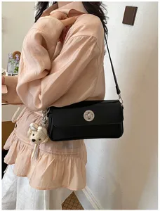 Detailed view of the stylish black shoulder bag with metal turn-lock and cute bear pendant.