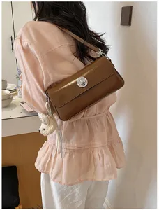 Brown leather shoulder bag detail, stylish crossbody handbag with cute bunny pendant for women.