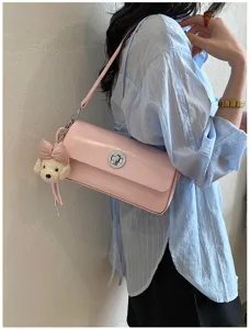 Pink leather shoulder bag detail showing metallic twist lock and cute bow bear plush pendant.