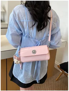 Pink shoulder bag detail view featuring metal twist lock and cute bear pendant charm accessory.