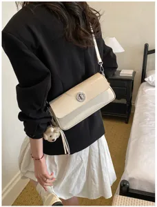 Minimalist beige crossbody shoulder bag with twist lock closure and bear charm detail.