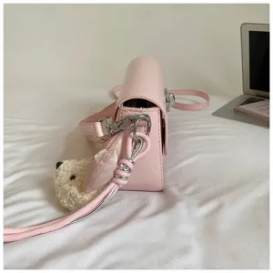 Detailed side view of a stylish pink crossbody bag featuring cute plush bear keychain charm.