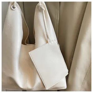 Detail shot of the minimalist off-white soft leather tote bag showing fine texture and pouch.
