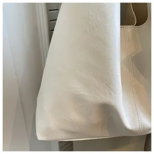 Close-up detail of minimalist white soft leather tote bag showing smooth texture and fine stitching.