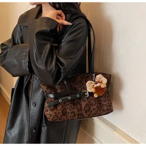 Detail view of winter vintage leopard print suede shoulder bag with cute plush doll charm.