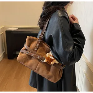 Detailed view of winter retro brown suede shoulder bag with decorative buckles and plush charm.