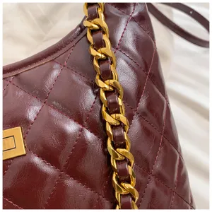 Detail shot of burgundy quilted shoulder bag with gold chain strap, premium leather texture