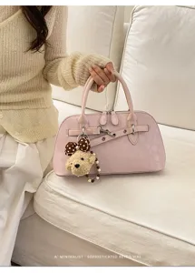 Détail de sac à main rose avec finition en cuir élégant, poignées solides et charmant pendentif.