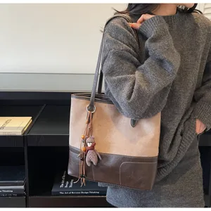 Detail view of the contrast color tote bag with bear charm in daily lifestyle setting.