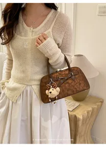 Détail du sac coquillage marron chiné avec pendentif ours mignon et fermoir métallique rétro.