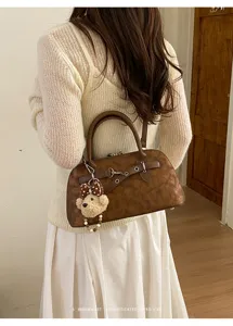 Détail de sac à main rétro texturé marron, élégant sac coquillage minimaliste avec charm ours.