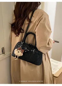 Vue détaillée d'un sac à bandoulière noir élégant en forme de coquillage avec pendentif.