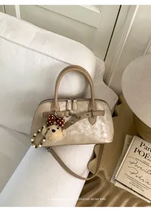 Vue détaillée du sac coquillage champagne élégant avec pendentif ours en peluche et métal.
