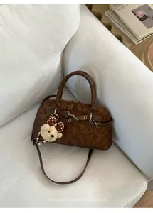 Détail du sac rétro marron avec texture douce, belle quincaillerie métallique et joli pendentif ours.