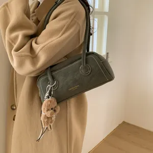 Chic dark green leather Boston shoulder bag with white stitching and cute plush dog charm.