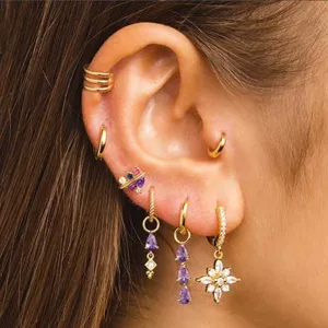 Gros plan détaillé d'un ensemble de boucles d'oreilles dorées serties de zircons violets.