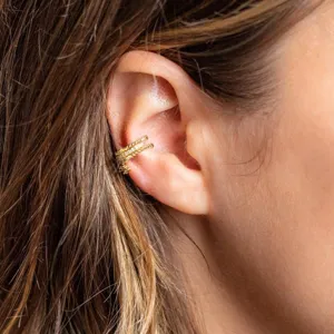 Nahaufnahme eines mehrschichtigen goldenen Messing-Ohrklemms, stilvoller geometrischer Schmuck.