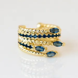 Nahaufnahme der goldenen Ohrklemme aus Messing mit blauen Steinen ohne Ohrloch zu tragen.
