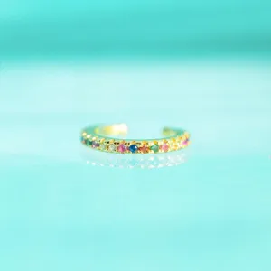 Gros plan détail d'une manchette d'oreille en zircon coloré, design minimaliste et pierres.