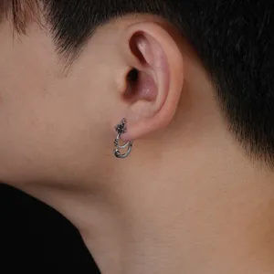Close-up detail of silver cross ear cuff, trendy men's gothic style punk jewelry piece.