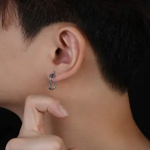 Close-up detail of cross ear stud worn on ear, minimalist trend men fashion jewelry.