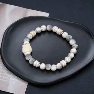 Vue rapprochée de l'élégant bracelet de perles blanches avec de fins détails sculptés de lion.