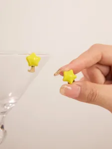 Detail view of yellow enamel star stud earrings with a glossy finish and metal backing.