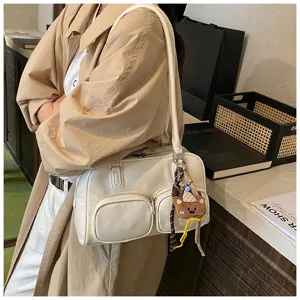 Dettaglio della borsa bowling rétro crema con ciondolo orsetto e tasche frontali pratiche.