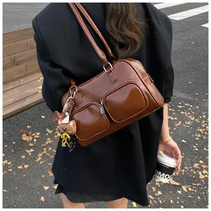 Vista dettagliata della borsa a spalla in pelle marrone stile bowling con tasche frontali.