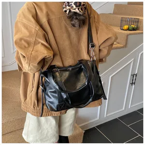 Vue détaillée d'un sac bandoulière Boston en cuir noir porté par un mannequin, chic.