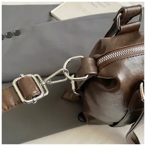 Détail de sac Boston en cuir PU marron foncé avec quincaillerie en métal et fermeture éclair.
