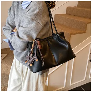 Black leather tote bag detail with cute dog charm, perfect for daily commuting and casual style.