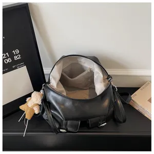 Detailed view of large capacity vintage black leather backpack with inner pocket and cute bear charm.