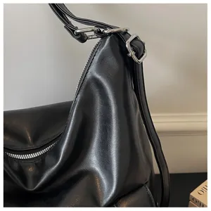 Black PU leather shoulder bag detail close-up showing metal zipper and adjustable buckle.