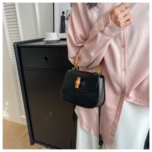 Vue détaillée du sac de selle noir rétro élégant avec une poignée en bambou et verrou.