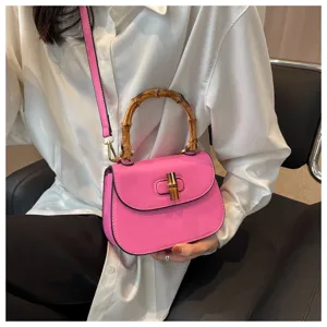 Sac bandoulière rose en cuir avec poignée en bambou élégante et sangle pratique chic.