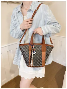 Detailed view of the stylish chevron bucket bag with brown leather trim and charms.