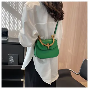 Sac de selle en cuir vert détail, poignée en bambou vintage bandoulière style mode d'été.