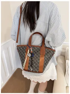 Chic women bucket shoulder bag with patterned canvas and stylish brown leather trim design.
