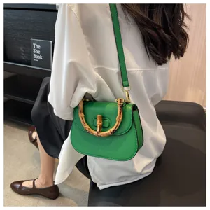 Vue détaillée du sac bandoulière en cuir vert avec poignée et bandoulière en bambou.