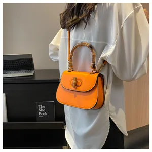 Sac bandoulière en cuir orange avec poignée en bambou unique et bandoulière élégante.
