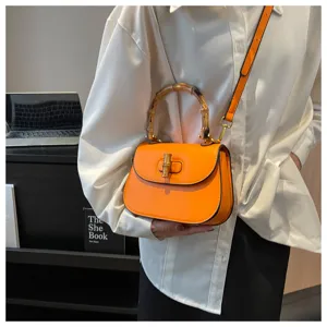 Sac à main en cuir orange doté d'une poignée chic en bambou et d'un fermoir tournant élégant.