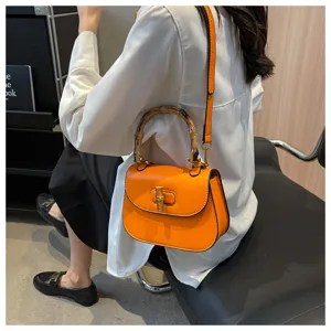 Élégant sac de selle en cuir orange avec poignée en bambou et design bandoulière pour femmes.