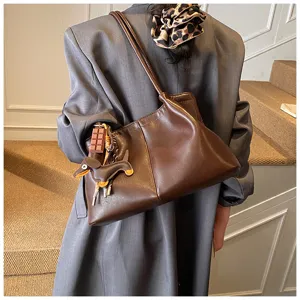 Brown soft leather shoulder bag detail showing cute dog charm and spacious tote design.