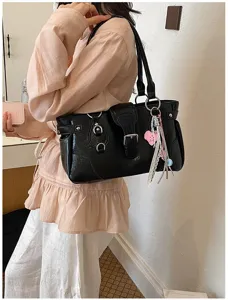 Black patent leather shoulder bag detail, stylish vintage underarm tote with metal buckles.