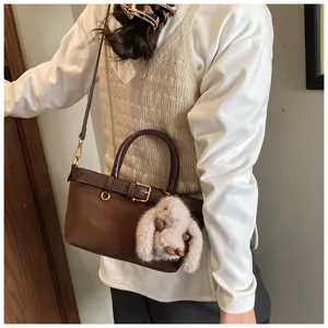 Vista di dettaglio di una borsa a tracolla marrone vintage in camoscio con ciondolo peluche.