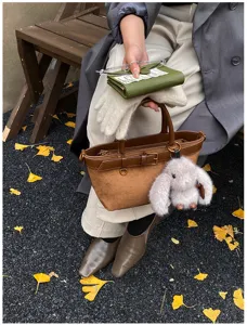 Primo piano di una borsa a mano retrò in pelle scamosciata marrone con ciondolo coniglio.