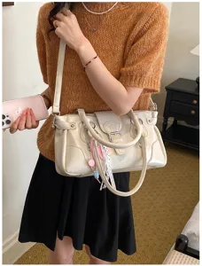 Detail view of the elegant beige leather shoulder bag with chic metal buckles and cute charms.